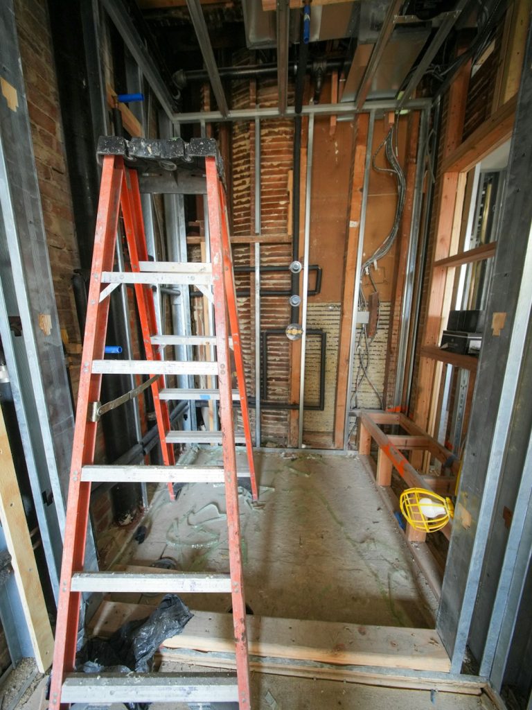 A three-story brownstone stands in mid-transformation, captured at the raw and honest “before” stage of a full interior renovation. These images document a moment that usually disappears once the walls are closed and the finishes are installed — exposed framing, stripped ceilings, rough staircases, and open corridors that reveal the building’s original structure and hidden history. Light spills in through skylights and tall windows, cutting through layers of dust and unfinished surfaces, creating a quiet contrast between decay and renewal. The space feels both industrial and intimate: narrow